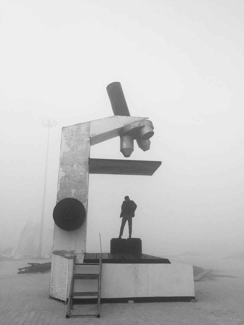grayscale photography of person standing on big microscope